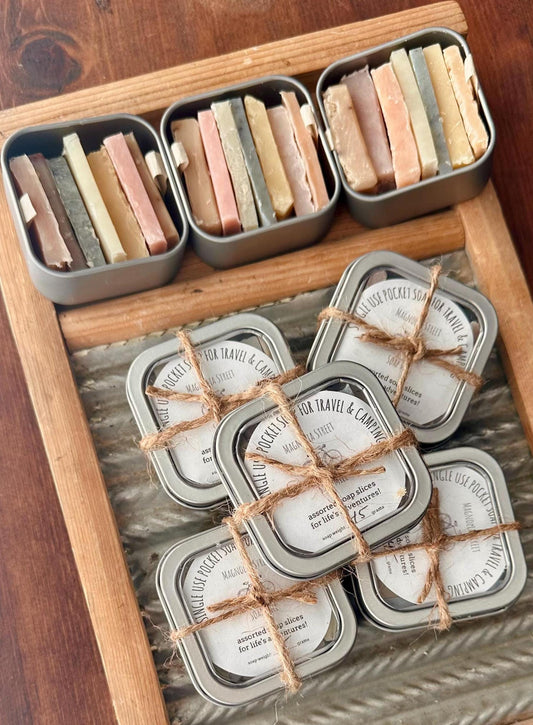 The image shows several tins of pocket soaps with assorted colors and labels, tied with string. Each tin contains multiple soap slices.