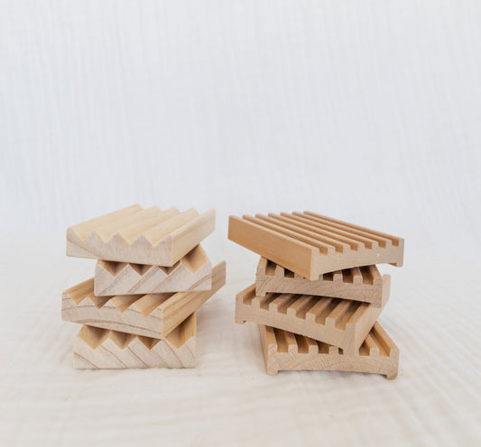 Two stacks of wooden soap dishes on a white background