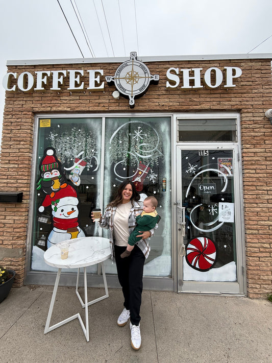 Photo of me holding my baby in front of a local coffee shop in my hometown.