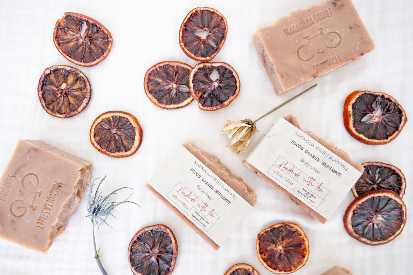 Natural Blood Orange Bergamot Bar soaps with dried orange slices and florals on a white background