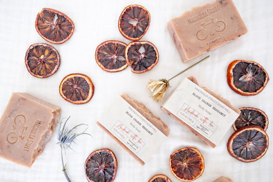 Natural Blood Orange Bergamot Bar soaps with dried orange slices and florals on a white background