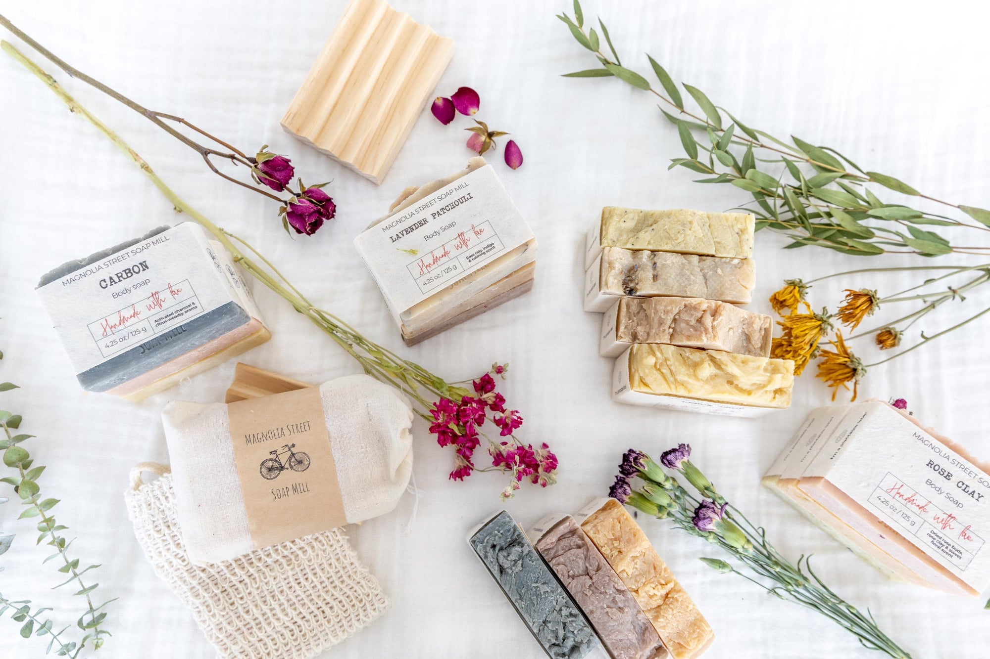 Overhead shot of a few of our handmade, natural soaps surrounded by botanicals.