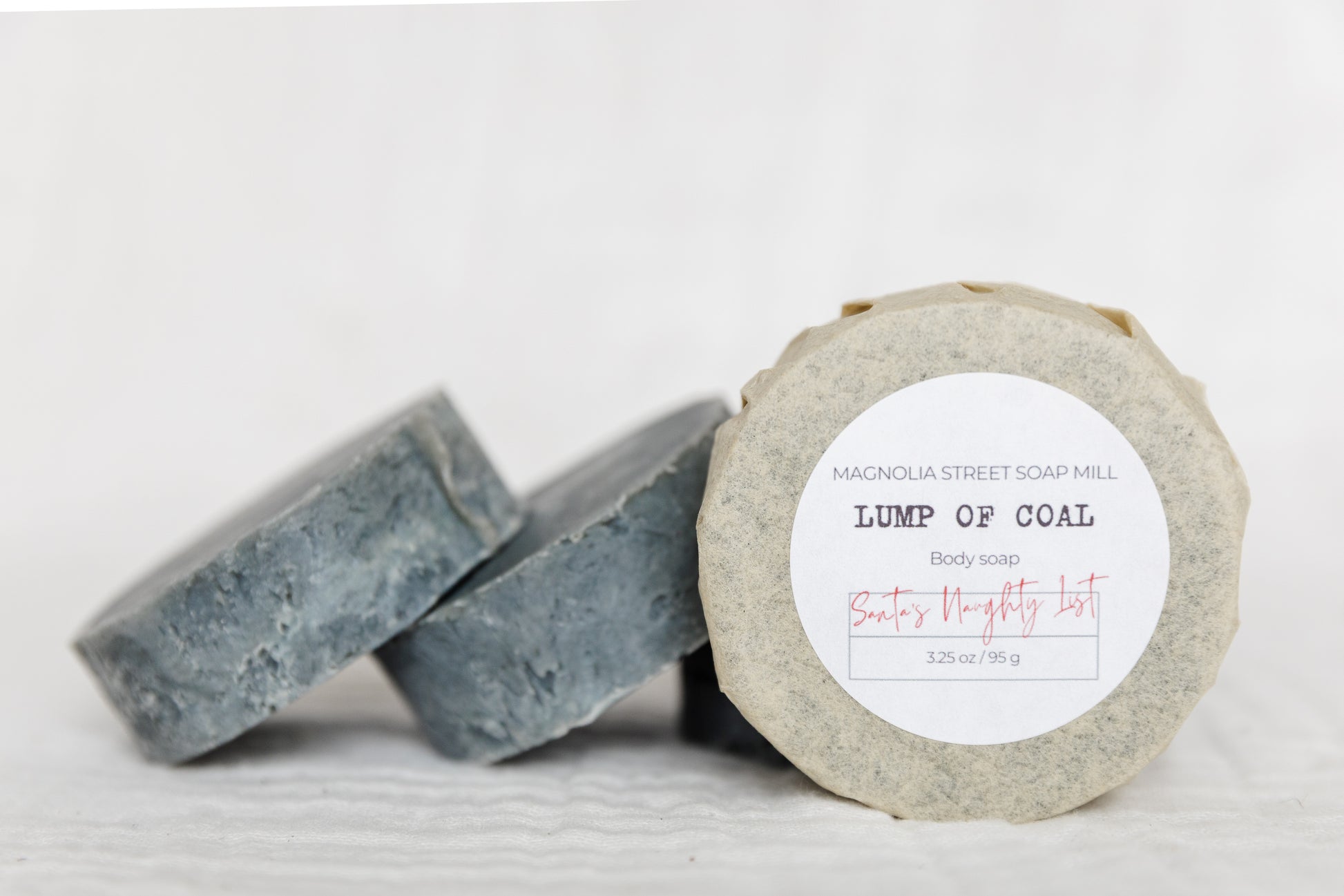 leaning stacks of Lump of Coal soap pucks. Label reads Santa's Naughty List