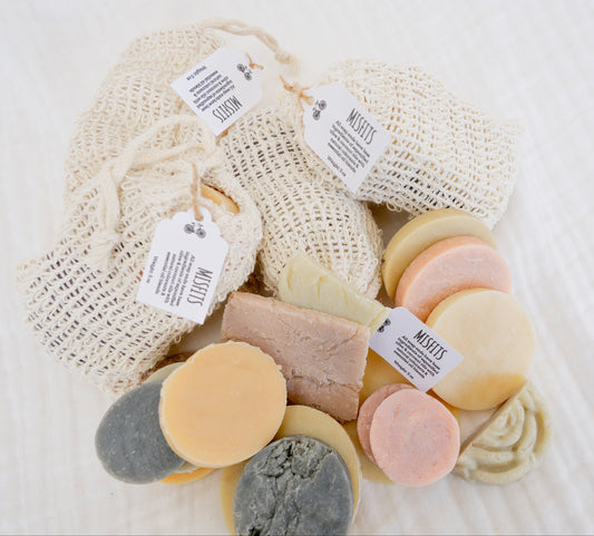 FOUR MISFITS BAGS WITH CONTENTS POURED OUT SHOWING WHAT TYPE OF SOAP PIECES ARE INSIDE. MIXED VARIETY OF SOAP ODDS AND ENDS, TOTALING ABOUT 5 OZ PER BAG.