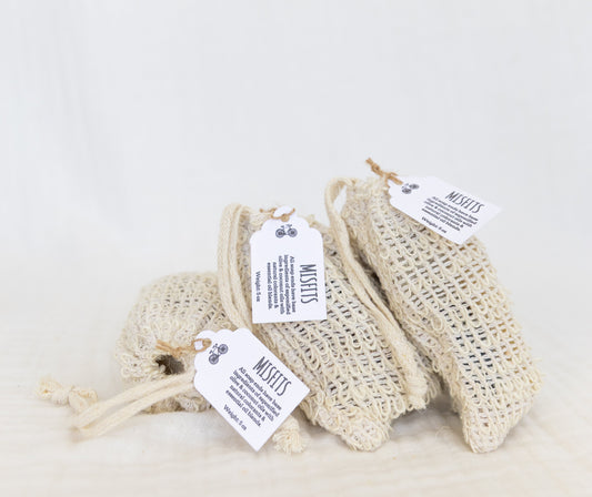 THREE SISAL SOAP BAGS FILLED WITH SOAP PIECES, STACKED NEXT TO ONE ANOTHER. 