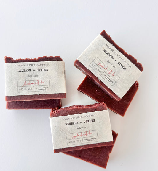 Six bars of handmade soap naturally colored with rhubarb powder wrapped in seed paper labels on a white background