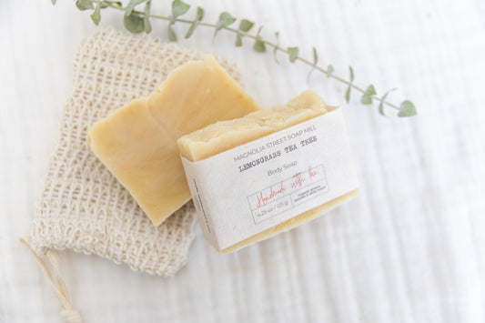 two bars of lemongrass tea tree soaps next to a sisal soap saver and dried eucalyptus branch.